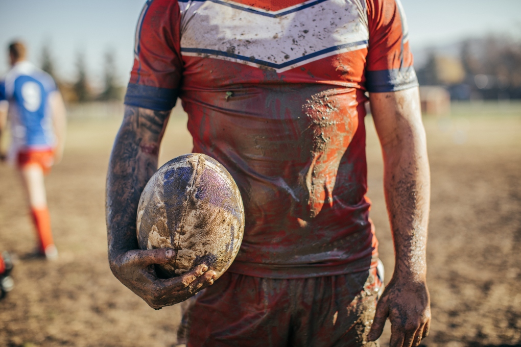 Muddy rugby player holding a ball
